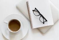 Induction button Photo of a table with a notepad, reading glasses and a cup of coffee