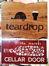 Photograph of the shop signs which hang on the wall outside the Teardrop bar and the Cellar Door