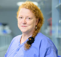 Photo of Prof Dame Sue Black in blue scrubs in a hospital