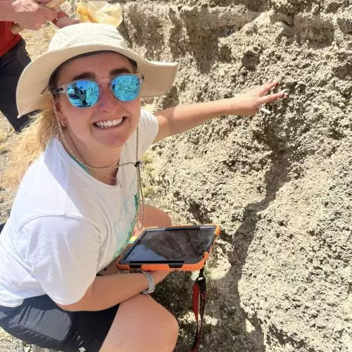 Emma smiles for the camera infront of a rock
