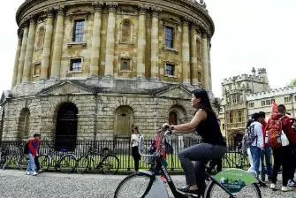 girl on a bicycle in front of the Radcliffe Camera in Oxford